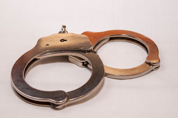 A single set of silver, metal handcuffs on a white background