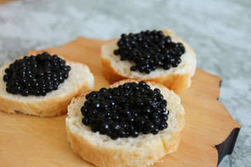 Top view of Tasty Sandwich with black caviar on White marble background.  .Free space for text. Black caviar. Luxurious culinary delicacy.