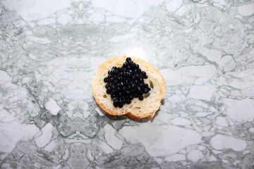 Top view of Tasty Sandwich with black caviar on White marble background.  .Free space for text. Black caviar. Luxurious culinary delicacy.