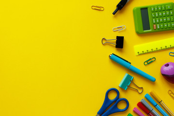 School supplies on yellow background. Back to school concept with space for text. Top view. Copy space. School office supplies.Creative desk with colourful stationery. Colored paper clip.