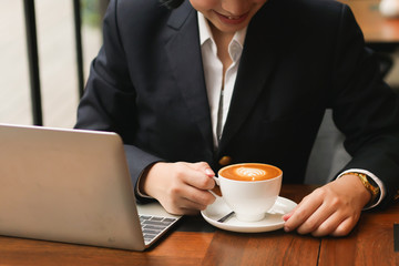 Asian woman using laptop and  drinking coffee  in coffee shop cafe