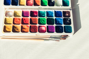 Watercolor paint and brushes well used on white wooden table with copy space for text.
