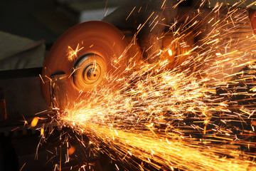 the worker cuts metal with a grinder and gloves protect him from sparks