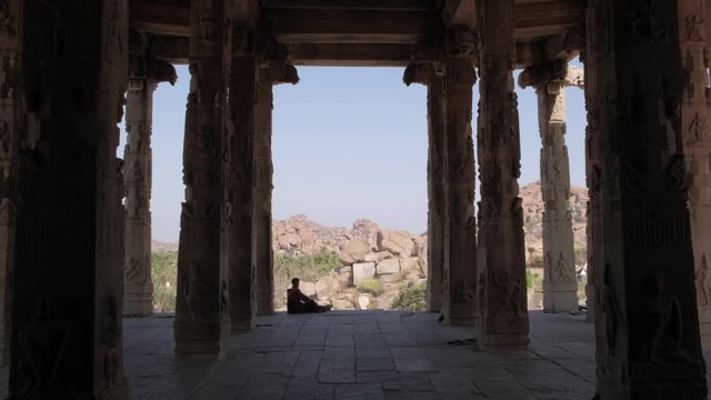 Silhouette of a lay resting inside the ruins of Hampi, an ancient village in the south Indian state of Karnataka with numerous ruined Hindu temple complexes from the Vijayanagara Empire.
