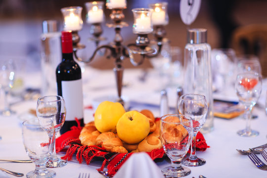 Banquet table with yellow quinces, buns or cakes and bottle of wine gathered in traditional Romanian towel. Holiday table decorated with traditional Moldovan elements and national symbols.