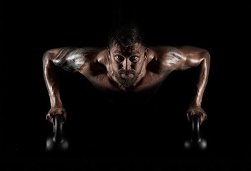 Handsome muscular man doing pushups on kettleball
