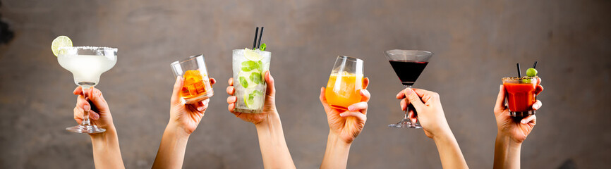 Hands holding classic cocktails on rustic background