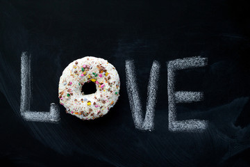 inscription love  on a chalk board and sweet glaze donut top view