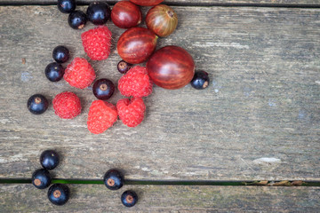 Garden berries on a wooden background. Garden berries raspberry gooseberry currants. Sweet berries.