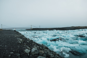 Sea shore covered in ice floes and bridge in Nordic landscape in Iceland