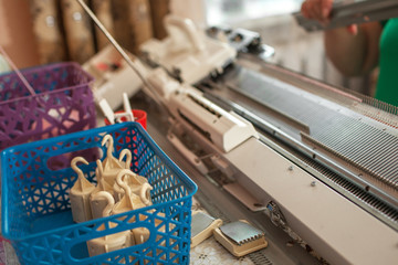knits on a knitting machine, working with her hands
