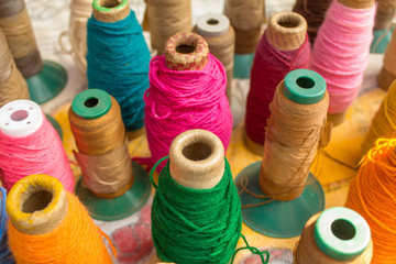 close-up of bright multicolored spools of thread stand on the table surface against a blurred background