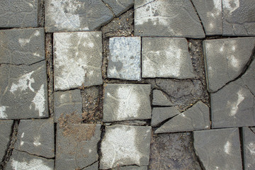 dirty gray broken square tile of different shapes and sizes in the ground top view. rough surface texture