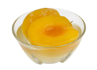 Halves of sweet ripe canned peaches with syrup in glass bowl isolated macro