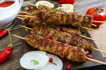 Delicious lula kebab on a wooden table. Chopped meat on wooden skewers, grilled. Eastern cuisine.