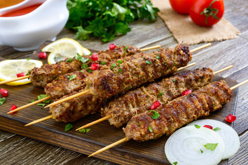 Delicious lula kebab on a wooden table. Chopped meat on wooden skewers, grilled. Eastern cuisine.