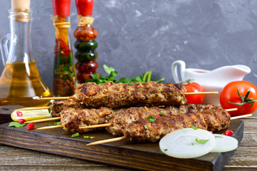 Delicious lula kebab on a wooden table. Chopped meat on wooden skewers, grilled. Eastern cuisine.