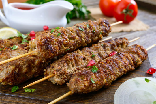 Delicious lula kebab on a wooden table. Chopped meat on wooden skewers, grilled. Eastern cuisine.