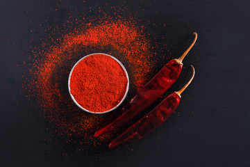 Red Chili pepper flakes and chili powder burst on black background - Powered by Adobe