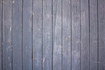 an old wooden fence of painted boards with gray peeling paint with cracks and scratches. vertical lines. rough surface texture