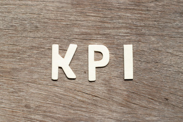 Alphabet letter in word KPI (Abbreviation of key performance indicator) on wood background