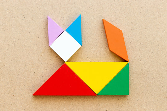 Color tangram puzzle in lying down cat shape on wood background