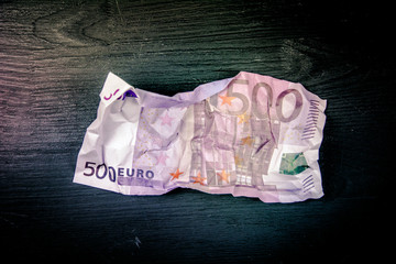500 euro crushed banknote on a black wooden background
