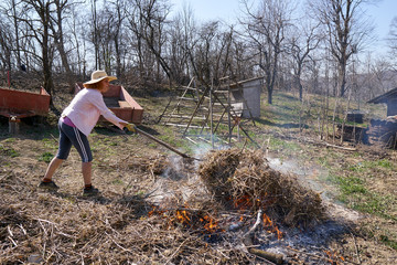 Woman farmer burning cut branches and leaves