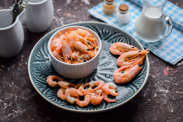 Shrimp peeled and unpeeled on a blue plate.