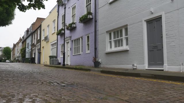 A pathway by houses painted in different colours on a rainy day.
