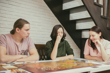 Group of friends sitting at the table. Young People having fun while playing board game.