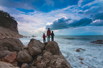 Silhouette of a woman and a children against the sea and sky.