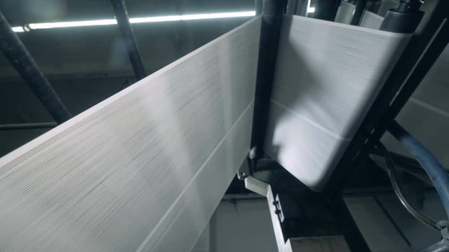 A loom weaving threads, working automatically at a factory.
