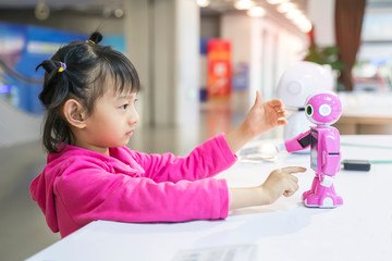 asian child extends a hand to the robot. concept of friendship between the robot and child