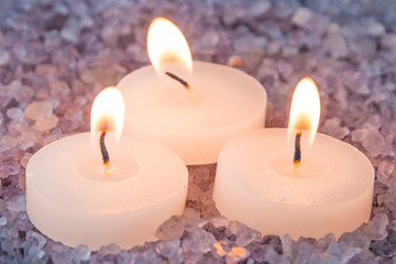 Obraz na płótnie Canvas preparations for the bath and aromatherapy : three decorative candle stand in aromatic sea salt with smell of lavender, close