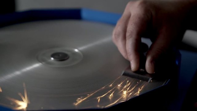 Slow-motion, worker sharpens a clipper blade on grinding machine, sparkles in slow-motion