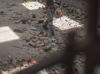 a man in dirty old clothes walks on stones and bricks from a ruined building