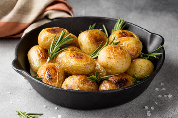 Fried (baked) whole small potatoes with rosemary and salt in a frying pan, ruddy crust, appetizing food