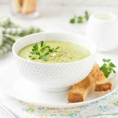 Green cream vegetable soup broccoli, peas, zucchini, spinach) with toast, croutons. Delicious vegetarian healthy spring, summer food on light background