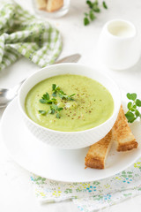 Green cream vegetable soup broccoli, peas, zucchini, spinach) with toast, croutons. Delicious vegetarian healthy spring, summer food on light background