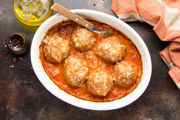 Meatballs in tomato sauce with cheese, baked meat cutlets from pork and beef in a baking dish. Delicious home cooked food