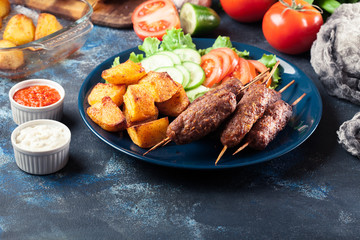 Grilled shish kebab served with fried potatoes