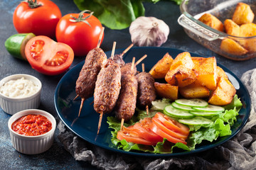 Grilled shish kebab served with fried potatoes