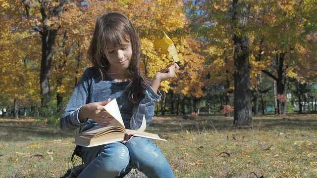 Child reading book outside. Cute little girl with with a book in the fall in nature.
