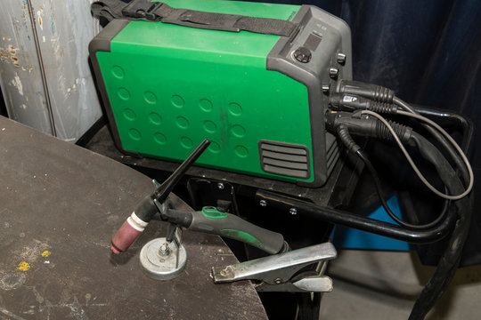 TIG welding torch and welder in background.