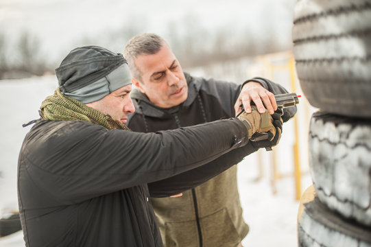 Instructor teaches student tactical gun shooting behind cover or barricade