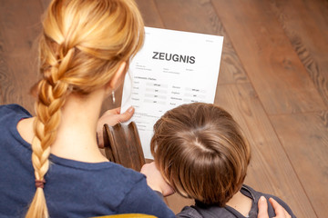 Mother and son are happy about the good school certificate - Translation: certificate day of birth disciplines music reading religion german english mathematics art maths very good, good