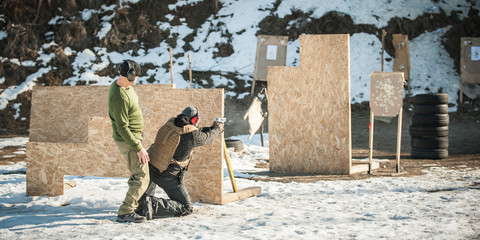 Instructor teaches student tactical gun shooting behind cover or barricade © guruXOX