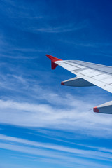 Fototapeta premium Wing of airplane flying above the white clouds in the blue sky . The theme of tourism and travel