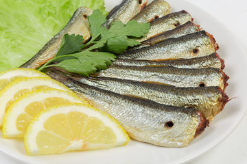 Smoked sprats with lemon and greens at selective focus